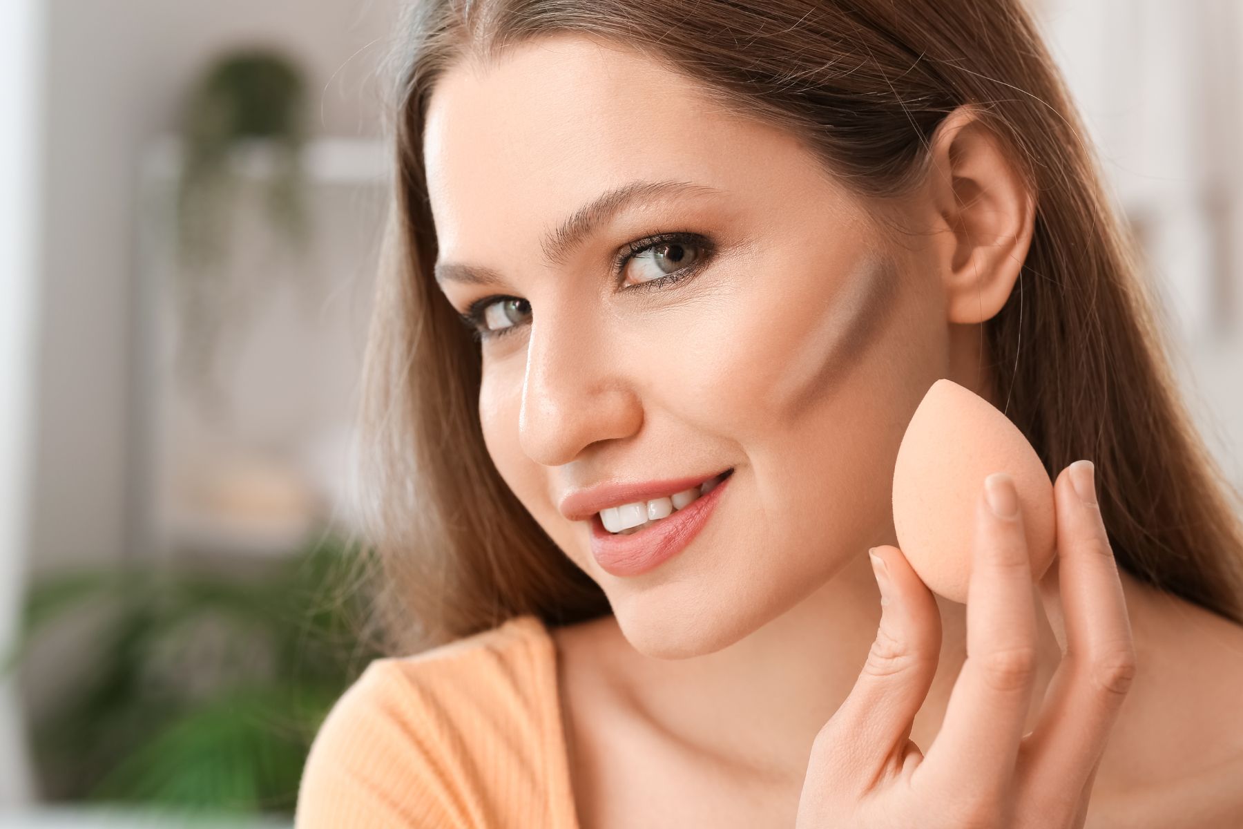 Girl contouring face with makeup sponge